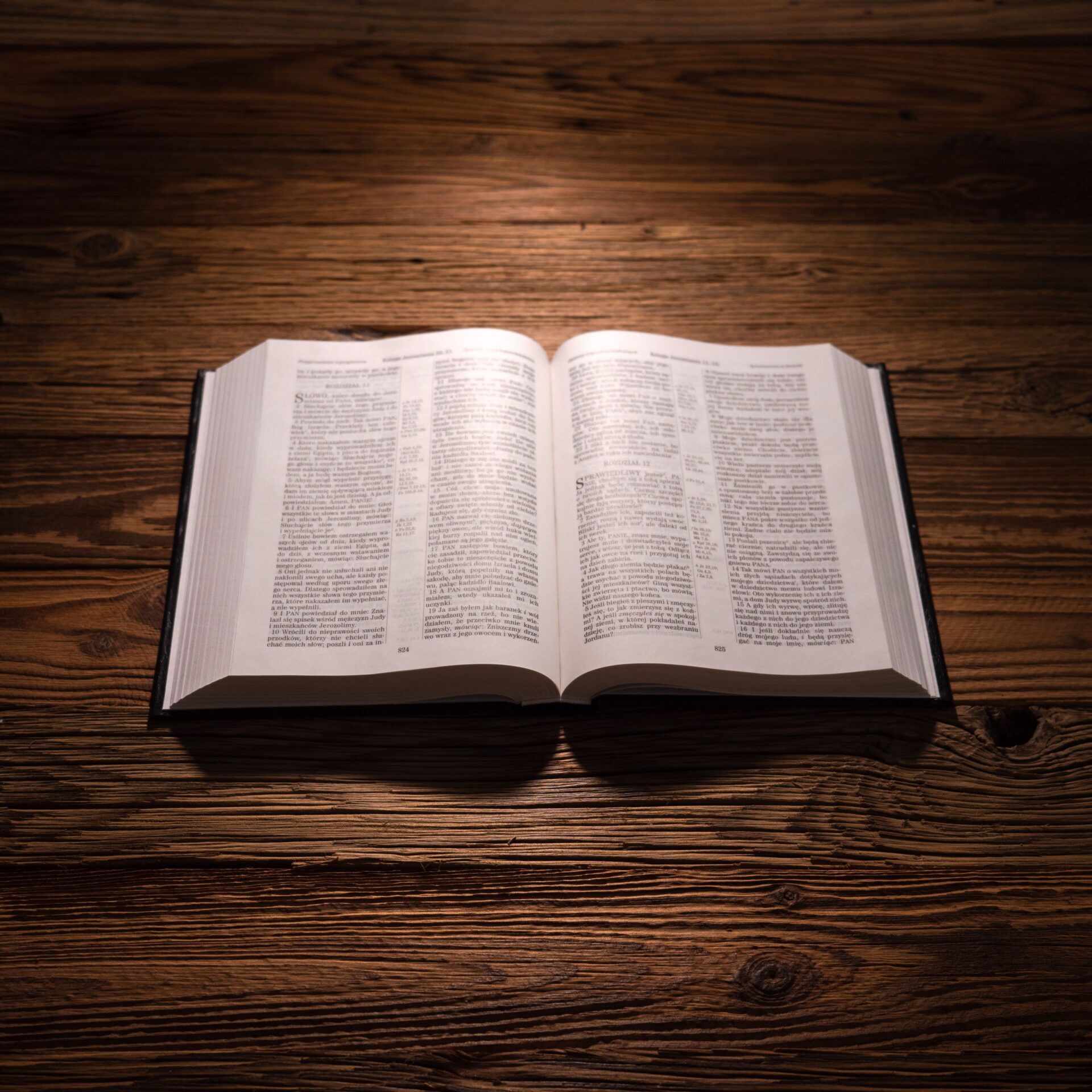 An open King James Bible on a wooden table in warm light
